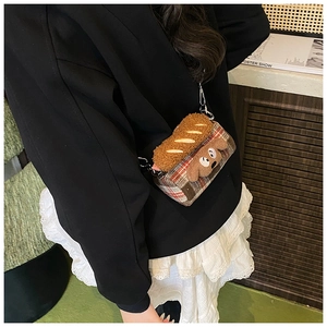 Detail of plaid crossbody bag featuring plush dog and baguette cartoon decorations