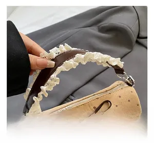 Detalle del bolso caqui de lunares con encaje blanco y asa de cuero marrón elegante