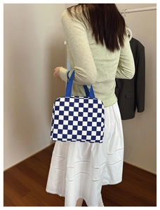 Blue and white checkerboard lunch bag with durable handles shown in a lifestyle setting