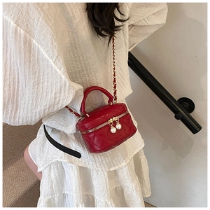 Detail of red quilted mini crossbody bag with pearl zippers and gold chain strap