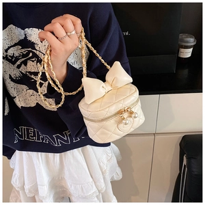 Detail of cream white quilted mini bag with oversized bow and double pearl zippers