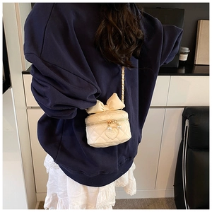 Detail of cream quilted crossbody bag with bow and dual pearl zipper closure