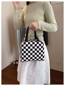 Close-up of handheld checkered lunch bag featuring black and white grid pattern with zipper