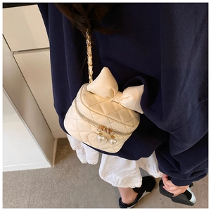 Back view of a girl wearing the cream quilted bow crossbody bag with gold chain strap