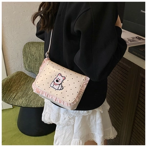 Detail view of cream polka dot crossbody bag with puppy patch and pink lace trim