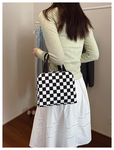 Close-up of the black and white checkered lunch bag showing durable woven handle and size