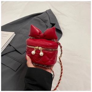 Detail of red quilted child's handbag with large bow and pearl zipper accents
