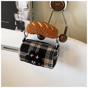 Detail of plush cylinder bag with plaid pattern and soft croissant shaped handle