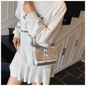 Detail of silver metallic crossbody bag with pink ruffles and cute puppy patch