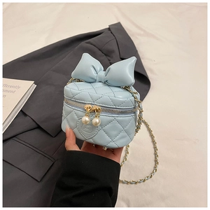 Detailed view of blue quilted mini box bag with bow, pearl zippers and gold chain strap