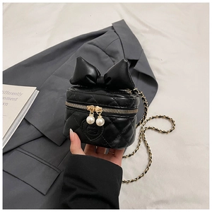 Detail of black quilted mini bag with leather bow, chain strap and pearl zipper charms
