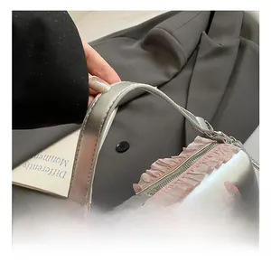 Détail du sac polochon argenté montrant la dentelle rose et les lettres imprimées