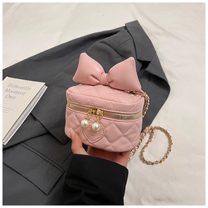Close-up of pink quilted mini bag with oversized bow and elegant pearl zipper pull detail