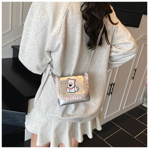 Silberne glänzende Umhängetasche mit rosa Spitzenbesatz und Cartoon-Hund Patch am Model