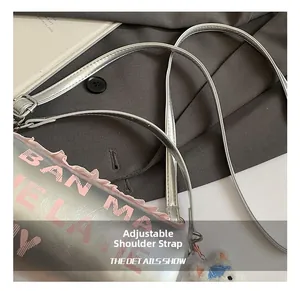Détail du sac cylindrique argenté avec volants roses, breloque ours et bandoulière