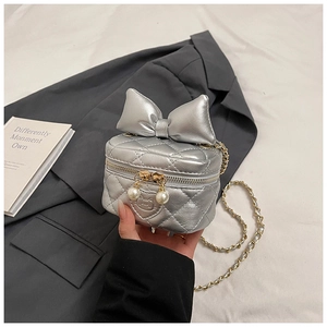 Close-up of silver quilted crossbody bag with oversized bow and pearl charm detail