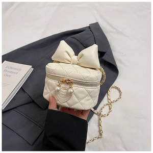 Close-up of cream quilted crossbody bag with oversized bow and pearl zipper pull details