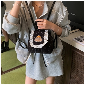 Détail du sac à dos en velours noir à pois avec bordure en dentelle et patch d'ours