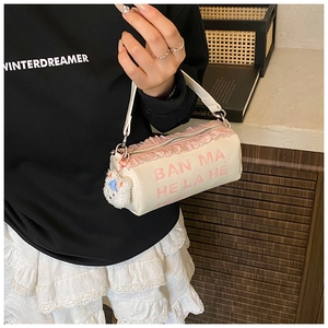Detail of cream white cylinder bag with pink lace trim and cute plush bear charm