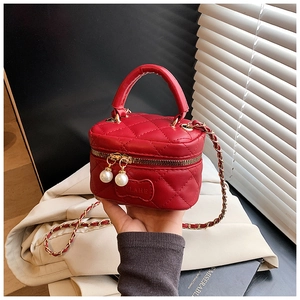 Gros plan du mini sac matelassé rouge avec fermetures en perles et bandoulière chaîne