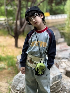 Close-up of a mini green crossbody bag worn with a stylish kids outdoor outfit
