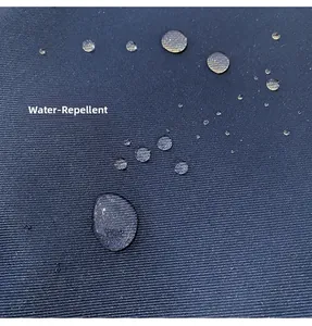 Close-up of dark blue water-repellent fabric showing beads of water on twill surface