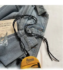 Detail of yellow canvas mini crossbody bag with black and white rope strap and zipper