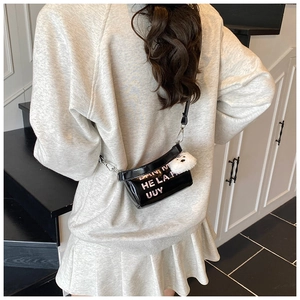 Detail of glossy black crossbody bag featuring pink lettering and plush panda charm