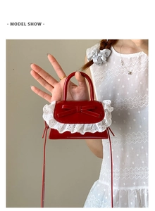 Close-up of red mini PU leather bag with bow and white lace trim detail