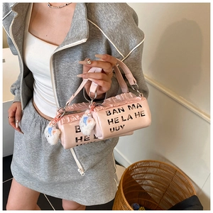 Detail of pink cylindrical PU leather bag with ruffle trim and white cat plush charm