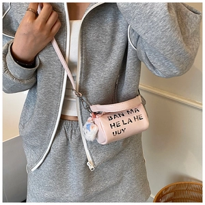 Pink barrel-shaped toddler crossbody bag with lace detail and plush cat charm