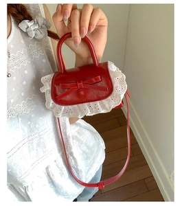 Close-up of red PU leather mini crossbody bag with bow and delicate white lace trim detail