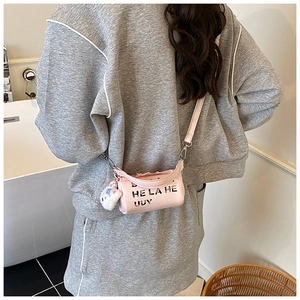 Lifestyle view of pink cylindrical kids crossbody bag with plush charm and letter print