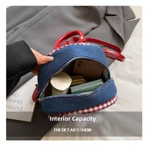 Close-up showing the interior capacity of this mini blue denim backpack with red handles