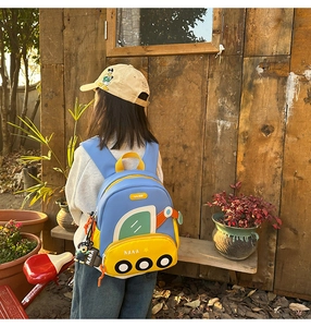 Detail of cute cartoon excavator backpack for kids with a small dog charm outdoors