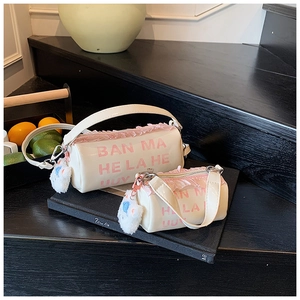 Detail of white leather cylinder bags with pink lace trim and plush pompom charms