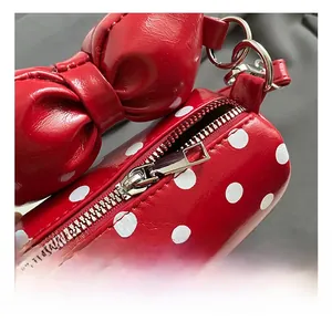 Close-up of red polka dot kids handbag with glossy finish and silver metal zipper detail