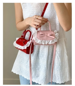 Close-up of mini PU crossbody bags with cute bow tie and white lace edge details