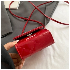 Detail of red quilted faux leather mini crossbody bag with glossy finish and strap