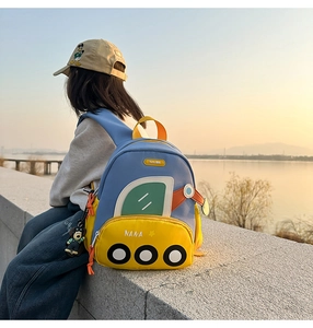 Detail of blue and yellow cartoon bus backpack with teddy bear pendant on waterfront
