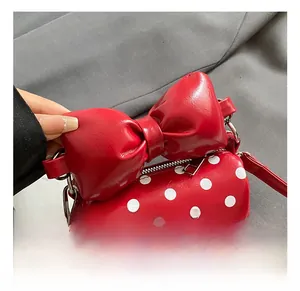 Detail of red polka dot mini handbag with a large bow and glossy patent finish
