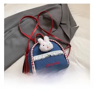Detail of denim mini backpack featuring plush rabbit head, lace trim, and red straps