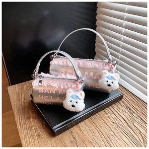 Detail of silver barrel bags with pink lace trim and plush puppy charms on books