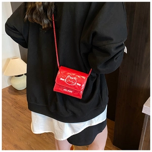 Detail of red quilted patent leather shoulder bag with white cartoon cat and lettering