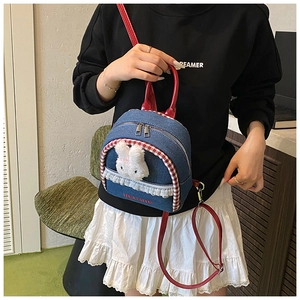Detail of denim mini backpack with cute plush bunny, lace trim and red leather straps