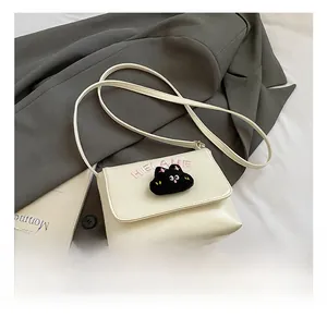 Detail of white leather kids crossbody bag with plush cartoon cat and embroidered logo