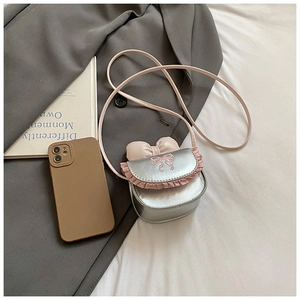 Detail of silver mini girl bag with pink lace trim and bow embroidery in a flat lay view