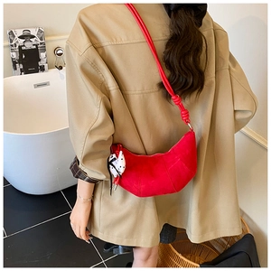 Detail of red crescent leather bag with visible stitching and polka dot scarf accessory