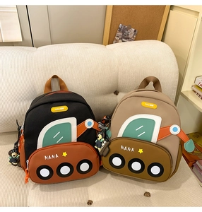 Detailed close-up of cute cartoon excavator backpacks in black and beige on a cozy sofa