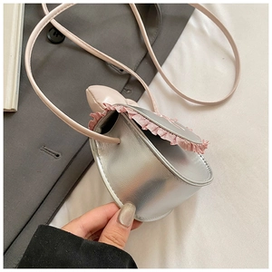 Detail of silver metallic kids crossbody bag with pink lace trim and leather strap